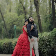 A classic portrait from an engagement shoot in a lush Pune garden. The woman's striking red gown and the couple's confident pose create a timeless and elegant image, showcasing a more formal and styled approach to pre-wedding photography.