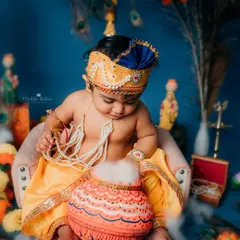 Caught in the act. This photo shows the baby looking down into his 'makhan handi' (butter pot), creating a classic and adorable narrative scene for his Bal Gopal photoshoot.