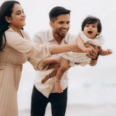 A moment of pure, uninhibited fun as parents playfully swing their laughing baby between them on the beach. Capturing these high-energy, joyful interactions is what makes family lifestyle photography so special.