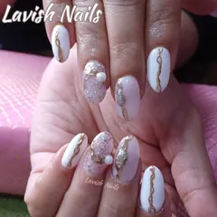 An ornate design featuring white and pink nails with gold swirls, glitter, and 3D pearl and rhinestone accents.
