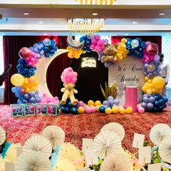 A wide view of our "We Can Bearly Wait" theme for a twin baby shower. This elaborate setup features a large, illuminated crescent moon prop, a custom backdrop, and a multi-colored balloon arch. We included details like teddy bear figures, a "Twice Blessed" neon sign, and transparent baby blocks to complete the look.