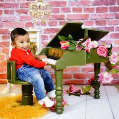 A future musician at our mini green piano. This prop, set against a brick wall with a chandelier, adds a touch of elegance and fun, and is always a hit with toddlers.