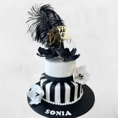 A chic black and white cake for Sonia's birthday. The design features bold stripes, elegant sugar flowers, and a dramatic black feather for a touch of Great Gatsby glamour.