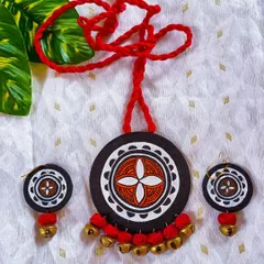 This circular pendant set features a hand-painted mandala-style design, edged with small brass ghungroos that create a lovely, subtle chime. The black, white, and red color combination is classic and bold. The adjustable red cord ensures a perfect fit for this ethnic jewelry piece.