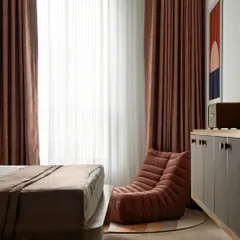 A custom-made lounger creates a cozy reading nook by the window. The console cabinet, with its textured panels and vibrant red knobs, was also designed and built by us.