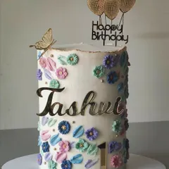 A closer look at the tall floral birthday cake. The buttercream flowers are piped in soft pastel shades and accented with small gold pearls for a delicate and pretty finish.