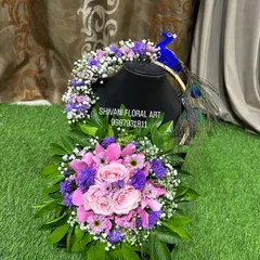 A beautiful baby shower prop set, including a floral purse and a matching hairpiece with a peacock motif, all made from real flowers.