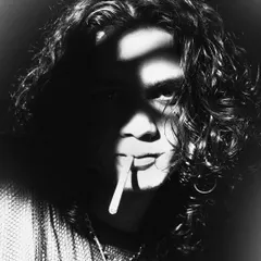 A classic, film-noir-inspired portrait. The use of a cigarette and the shadow cast across the model's face create a timeless, moody, and mysterious character.