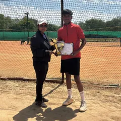 A young competitor receives his winner's trophy from the tournament director. This image is from our monthly prize money event where players compete for cash and Luxilon strings.