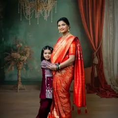 A beautiful moment between a mother and her daughter during a traditional maternity shoot. The mother's glowing presence in a red saree is complemented by her daughter's loving embrace.