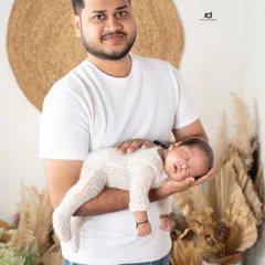 A proud father holding his sleeping newborn. You can see the love and protection in his arms. It's a beautiful portrait of fatherhood.