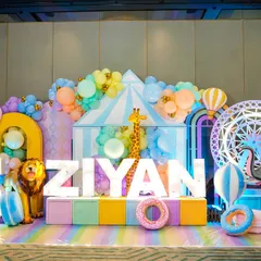 An adorable pastel carnival photo stage for a 5th birthday, featuring a light-up ferris wheel, animal props, and the birthday boy's name in giant letters.
