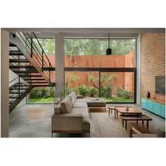 The double-height living room is the heart of the home, with floor-to-ceiling windows that look out onto the private garden. This visual connection to the outdoors makes the entire space feel larger and more open.