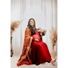 This image showcases the beautiful setup for the traditional maternity shoot, with pampas grass and a soft white backdrop complementing the vibrant saree.
