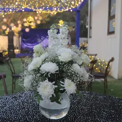 Elegant centerpieces elevate the guest experience. For this evening event, we used simple yet beautiful arrangements of white flowers on sequined tablecloths to add a touch of class to each table.