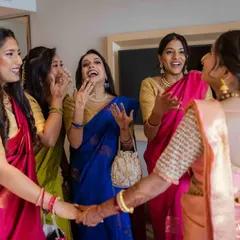 The bride and her bridesmaids share a laugh and hold hands, a beautiful moment of friendship and support.