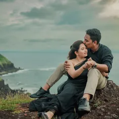 A breathtaking view from a pre-wedding shoot in Kokan. The couple shares an intimate moment on a rocky cliff, with the vast expanse of the sea and coastline creating a truly epic and romantic scene.