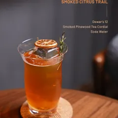 The Smoked Citrus Trail, featuring Dewar's 12 and a smoked pinewood tea cordial. This drink offers bright, smoky notes with a clean soda water finish.