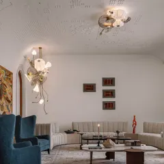 Another view of the formal living room, showcasing the interplay of textures and forms. The deep blue chairs provide a pop of color against the neutral palette, while the custom lighting by Olie Lighting acts as jewelry for the ceiling.