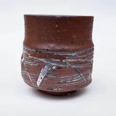 This teabowl has a rough, earthy texture with white slip creating a stark, abstract pattern. It's a piece that holds emotion and is more than just a bowl.