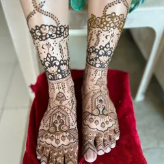 This elegant foot design combines traditional peacock and jharokha motifs on the feet with a modern, bold floral band around the ankles.