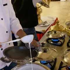 Our chef carefully prepares the batter for a fresh appam at a live cooking station. This is a key part of our South Indian wedding catering service, offering guests an authentic culinary experience.