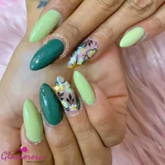 A nature-inspired design with a mix of solid dark green, light green, and accent nails featuring hand-painted white and yellow flowers on a sheer base.