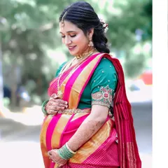 A solo portrait of the mother-to-be, cradling her bump with a gentle smile. Her traditional silk saree and jewelry add to the richness of the Seemantham celebration.