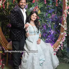 A happy couple at their engagement. The groom-to-be is wearing a black textured tuxedo from my collection, which pairs beautifully with his fiancée's light blue lehenga.