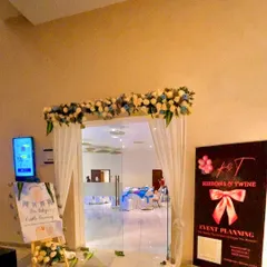 The entrance to the cradle ceremony, decorated with a floral garland, white drapes, and our company standee.
