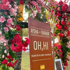 Let the Sangeet shenanigans begin. This fun "Oh, Hi" sign, framed by vibrant red and pink flowers, directed guests to the party at a lively beachside Sangeet.