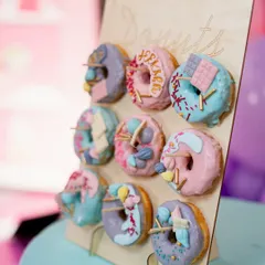 A colorful donut wall is a fun and interactive treat for guests. These were custom-decorated to fit the pastel Candyland party theme.