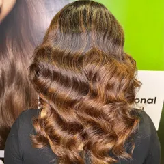 The stunning "after" result. We added rich caramel highlights and styled her hair in soft waves to show off the new color.