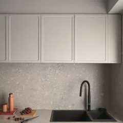 The kitchen countertop and backsplash are made from a durable and beautiful grey terrazzo. Paired with a modern black sink and faucet, the look is clean, timeless, and practical.