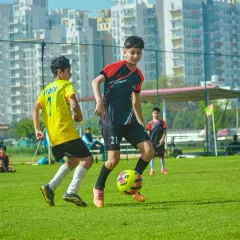 Young players compete for the ball with the city skyline in the background at our Gurgaon venue. This image shows the vibrant, energetic atmosphere of our youth leagues.