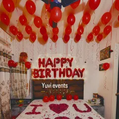 Another example of a romantic birthday room setup. The combination of red balloons, rose petals, and 'Happy Birthday' foil letters creates a memorable surprise.