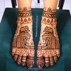 Symmetrical mehendi for the feet featuring majestic elephants. The design also includes hanging jhumkas and intricate patterns covering the entire foot, perfect for a bride.