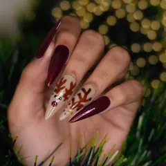 A clear, top-down view of the reindeer nail art set. This angle highlights the sharp stiletto shape of the extensions and the precise details of the hand-painted character.