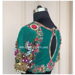 This modern back design on an emerald green blouse uses a sheer net fabric as a base. A keyhole cutout is framed with heavy, multi-dimensional floral beadwork and sequins for a dramatic effect.
