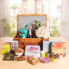 A cheerful and abundant wedding hamper in a picnic basket, filled with sparkling juice, cookies, snacks, and decorative items for the happy couple.