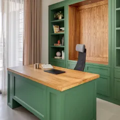 This custom-designed home office in Dubai Hills features a bold bottle green finish paired with a warm oak wood desk and integrated shelving. We designed this space to be a functional and personal sanctuary, balancing rich color with natural light to create a calm, focused environment.