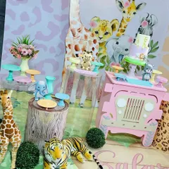 A close-up of the dessert table from our pink safari theme. We use themed props like tree stump plinths and a miniature jeep to display treats, ensuring every detail fits the jungle adventure.
