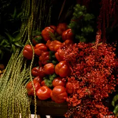 A close-up on the surprising textures within the arrangement. Here, bright red bell peppers are nestled amongst cascading green foliage and delicate red florals. I believe in adding unexpected elements that delight the senses and make you look twice.