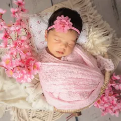 An overhead view of a baby girl wrapped cozily and surrounded by beautiful cherry blossoms. This angle is perfect for capturing their sweet, tiny features.