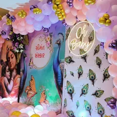 Another view of the Krishna themed baby shower, showing the 'Oh Baby' neon sign and the peacock feather details on the side panel.