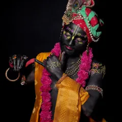 This look focuses on the transformation into Lord Krishna, using dark body paint, floral details, and traditional attire.
