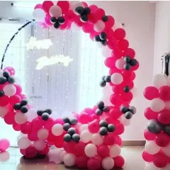 A modern and stylish circular balloon frame in pink, white, and grey. This setup includes a string light curtain and a neon sign, creating a perfect photo booth or backdrop for a chic first birthday or baby shower.