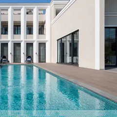 A close-up of the villa's poolside facade, where the architecture provides a stunning backdrop for relaxation and entertainment. The interplay of light, shadow, and water is a key element in our design philosophy.