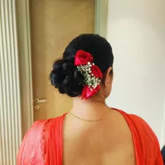 A low, intricate bun adorned with fresh red roses and baby's breath. This style is perfect for a bride who wants a classic floral look that is both elegant and secure.