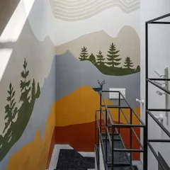 A custom mural adorns the staircase wall, turning a functional space into an artistic journey. The design depicts a serene mountain landscape, adding color and personality.